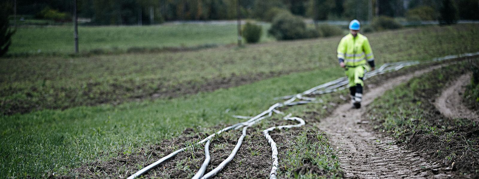 Cable worker walking along a medium voltage cables laying on the ground waiting to be installed